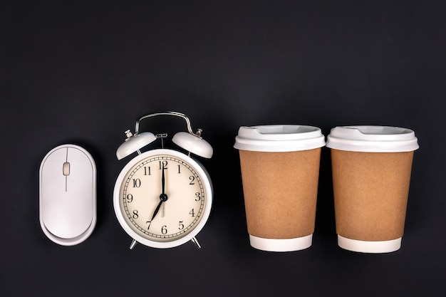 Free photo paper cups alarm clock and a computer mouse on a dark background top view