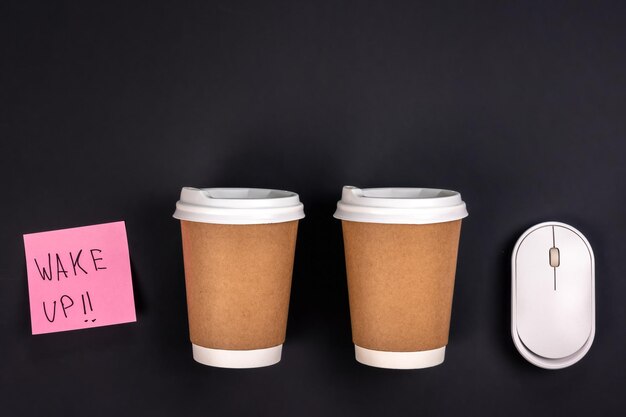 Paper cups computer mouse and paper sticker on a dark background top view