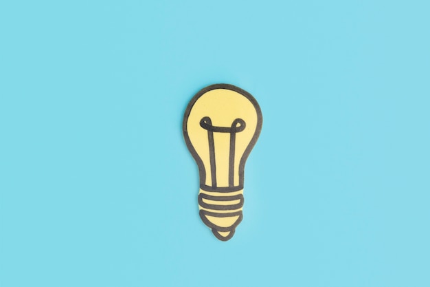 Free photo paper cut out yellow light bulb on blue background