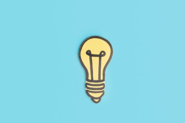 Paper cut out yellow light bulb on blue background