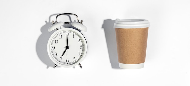 Free photo paper disposable cup and alarm clock on a white background top view