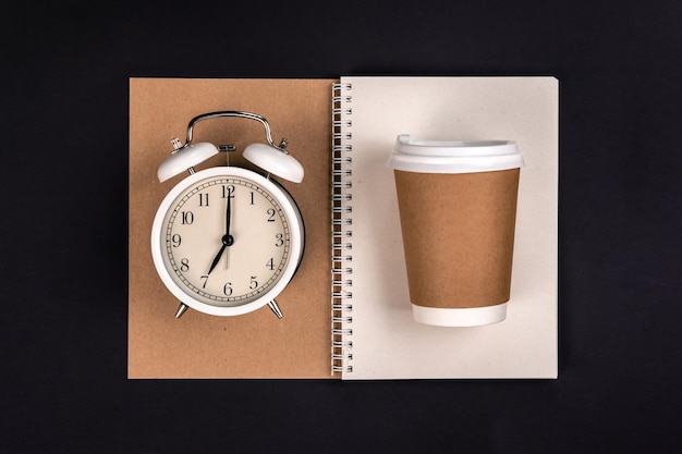 Free photo paper disposable cup notebook and white alarm clock top view
