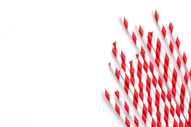 Free photo paper drinking straws with red stripes ornament on a white background flat lay