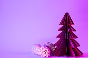 paper fir tree with christmas balls on blue background with neon light