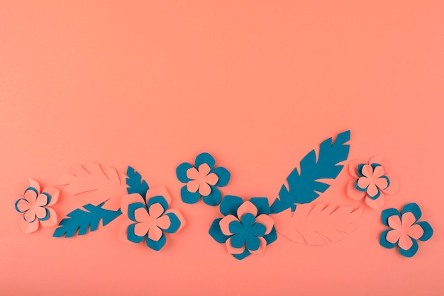 Paper flowers and leaves on coral background