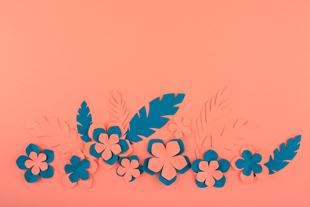 Paper flowers and leaves on coral background