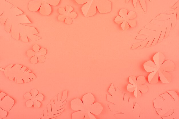 Paper flowers and leaves on coral background