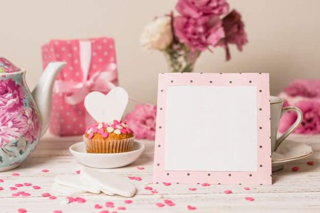 Paper frame near delicious cake, present box and teapot