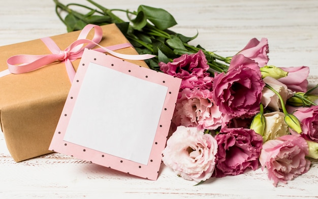 Бумажная рамка возле подарочной коробки и цветов
