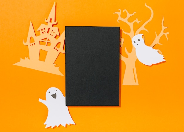 Paper ghosts with castle and tree laid around black sheet