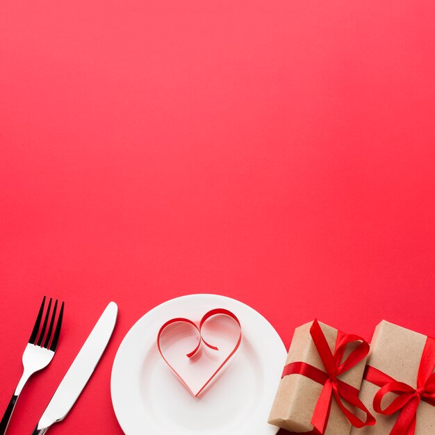 Paper heart shape on plate with presents and cutlery