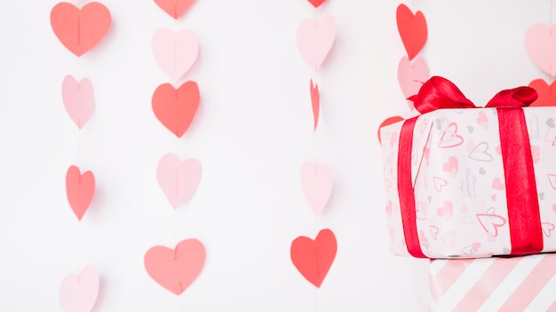 Paper hearts hanging on rope near gift boxes 