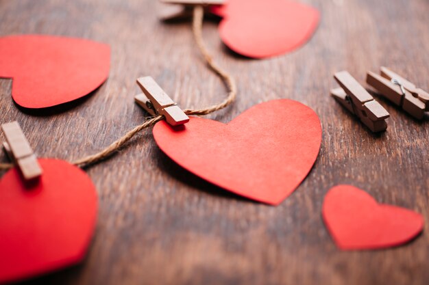 Paper hearts pinned to rope on wooden table