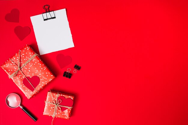 Бумага возле подарочных коробок с орнаментом сердечками, клипсами и лупой