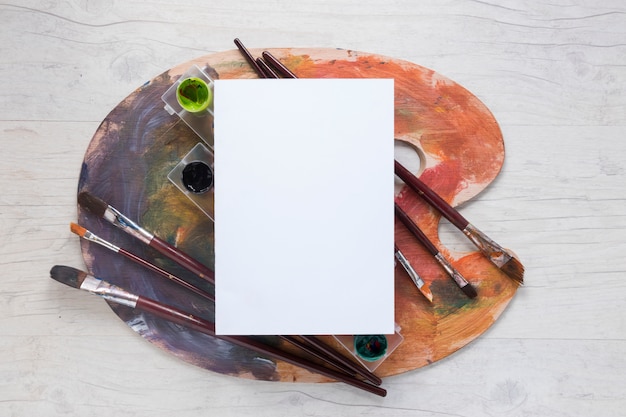 Free photo paper on palette with gouache and paint brushes