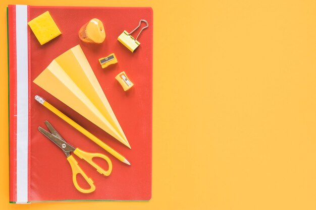 Paper plane surrounded by orange stationery objects