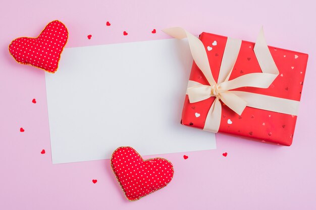 Paper sheet near hearts and cute gift