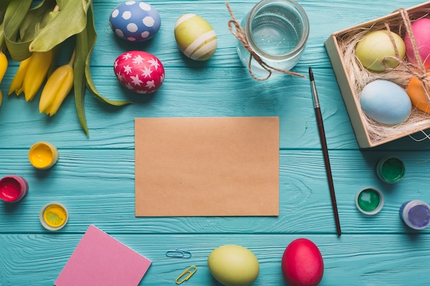 Лист бумаги рядом с краской и яйцами