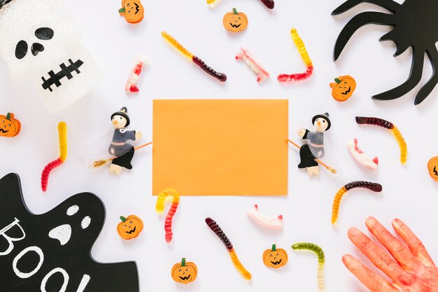 Paper sheet with Halloween decorations and candies with bloody hand