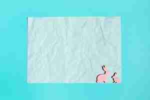 Free photo paper sheet with small wooden rabbits on table