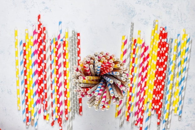 Free photo paper straws of different colors on light tablewith