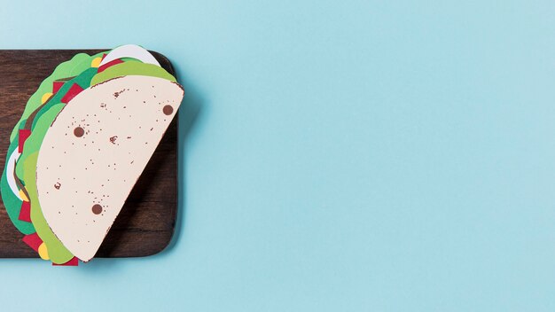 Paper taco on wooden board flat lay