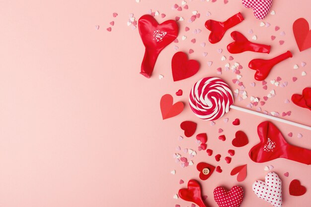 Paper valentines day hearts with sweets on pink