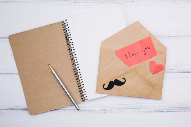 Paper with I love you title near heart and mustache on letter near notepad