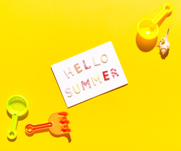 Free photo paper with inscription hello summer and scoops for sandboxes