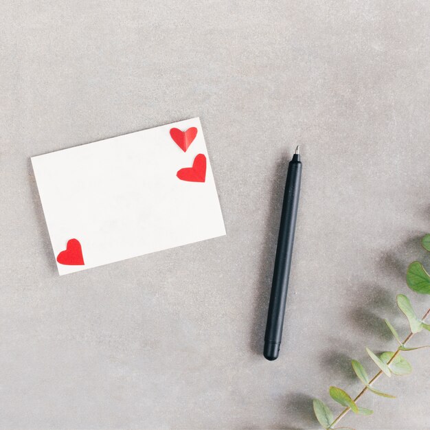 Бумага с сердечками возле ручки и растения