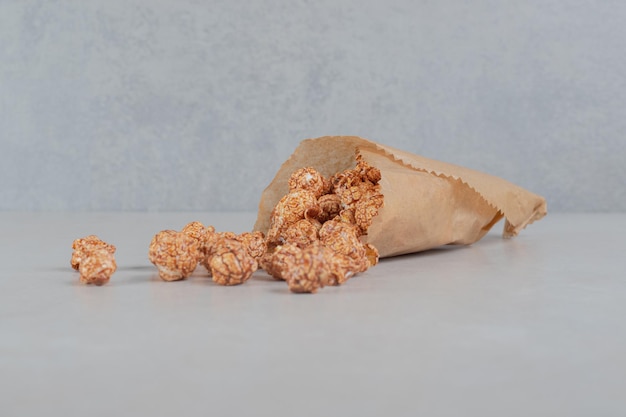 Paper wrapping filled with candy coated popcorn on marble table.