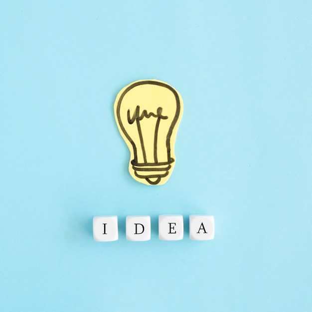 Paper yellow bulb with white ideas blocks over blue colored background