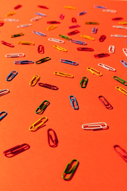 Paperclips on orange background high angle