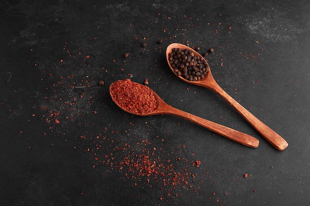 Paprika and black pepper in wooden spoons. 