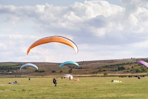 구름과 푸른 하늘 아래 아름 다운 녹색 풍경을 비행하는 패러 글라이더 실루엣.