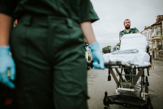 Squadra paramedica che fa rotolare una barella su una strada