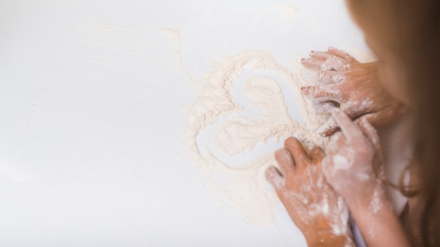 Free photo parent and child making heart from flour