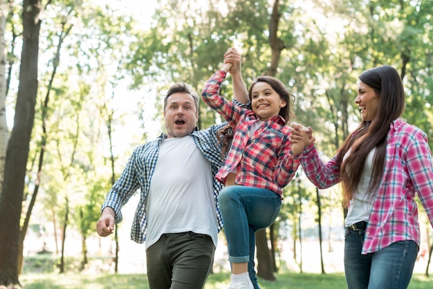 Parent lifting their daughter at park