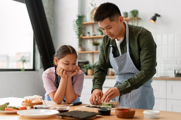 子どもに寿司を作る方法を教える親