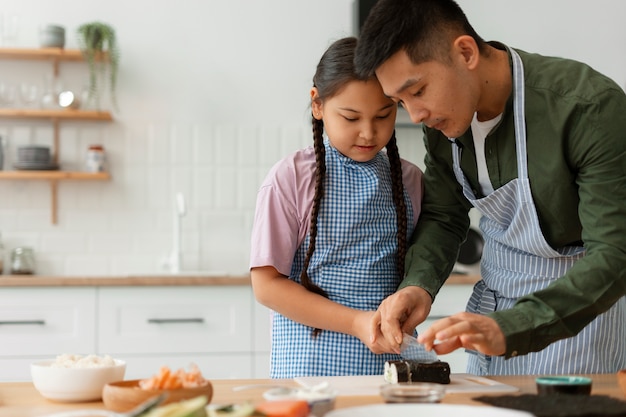 Foto gratuita genitore che insegna al figlio a fare il sushi