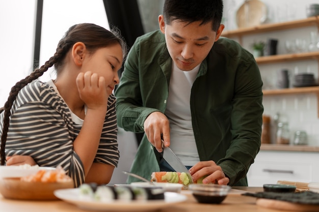 子どもに寿司を作る方法を教える親