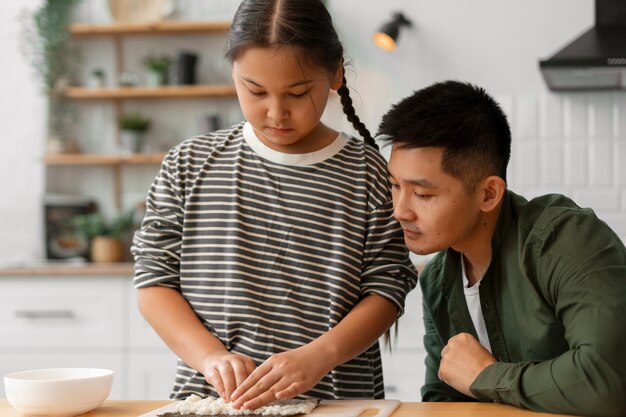 子どもに寿司を作る方法を教える親