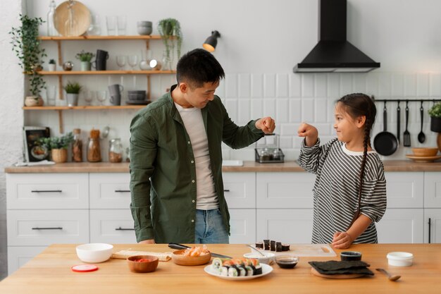 Free photo parent teaching kid how to make sushi