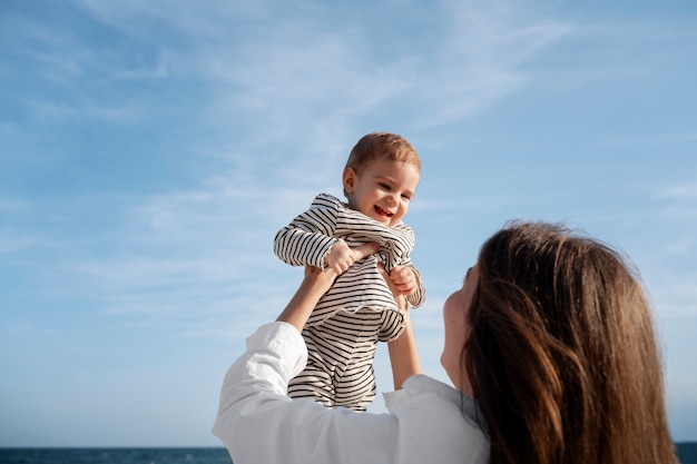 Free photo parent with a baby on the beach at sunset