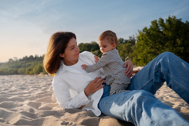 Free photo parent with a baby on the beach at sunset