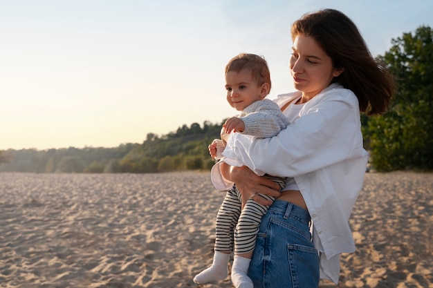 Foto gratuita genitore con un bambino sulla spiaggia al tramonto