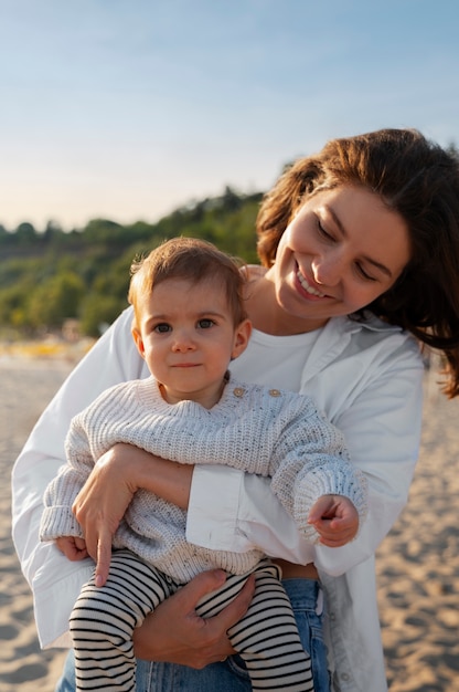 Foto gratuita genitore con un bambino sulla spiaggia al tramonto