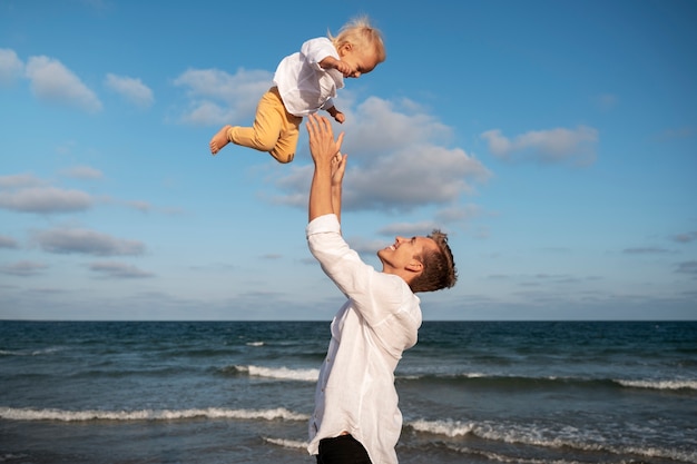 Foto gratuita genitore con un bambino sulla spiaggia al tramonto