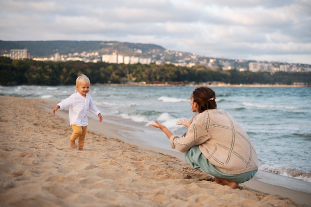 Foto gratuita genitore con un bambino sulla spiaggia al tramonto