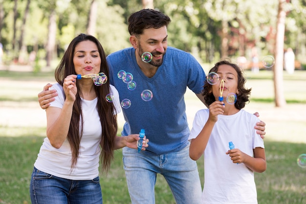 Parents and boy having a great time blowing bubbles at the park